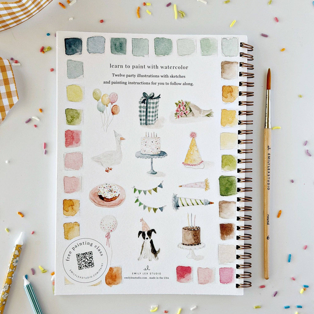 Watercolor workbook page with illustration guide, spiral binding, and watercolor swatches.
