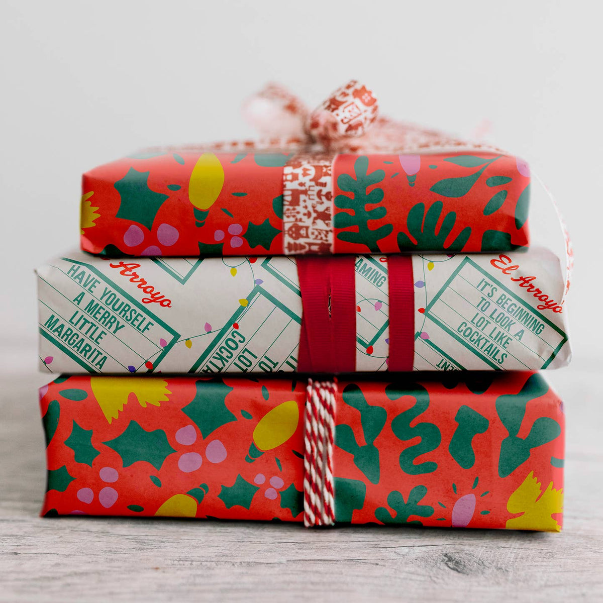 Holiday wrapping paper with red, green, and cream festive cocktail print on wrapped gift