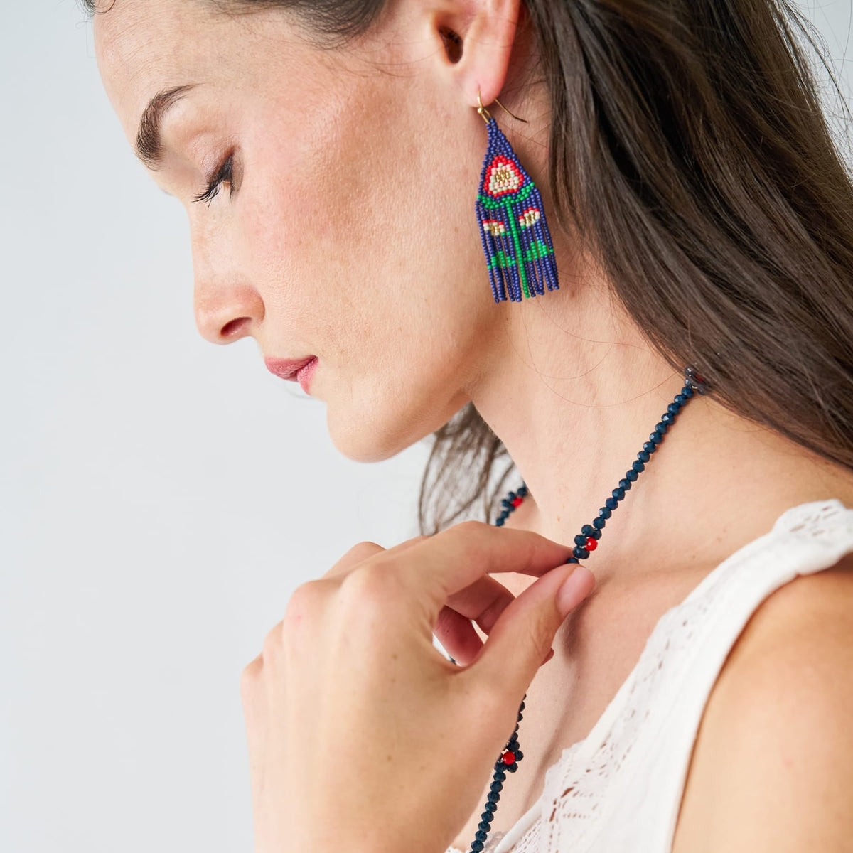 Blue and multicolor beaded floral tassel earrings on gold hooks, worn on model