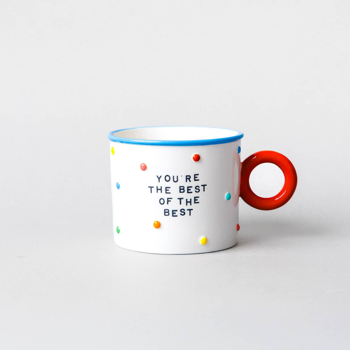 White ceramic mug with red handle, blue rim, colorful dots, “You’re the Best of the Best”