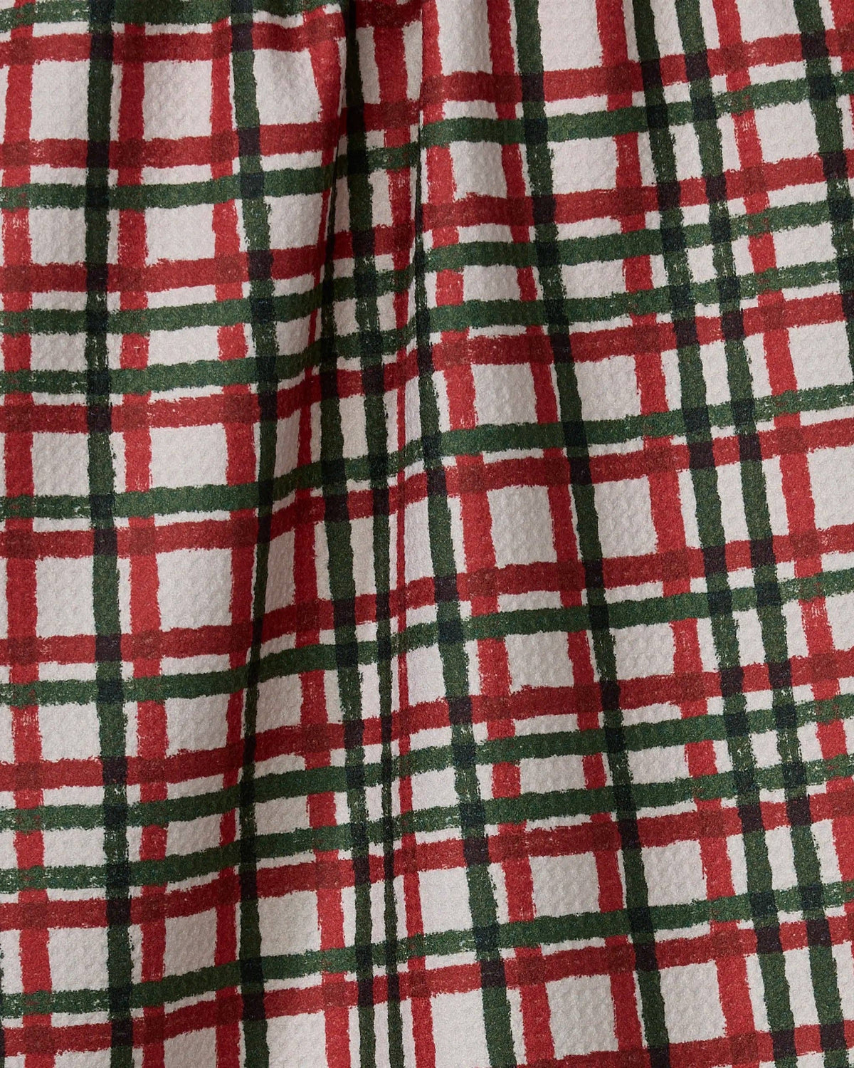 Plaid tea towel fabric close-up in red, green, and white with gathered seam