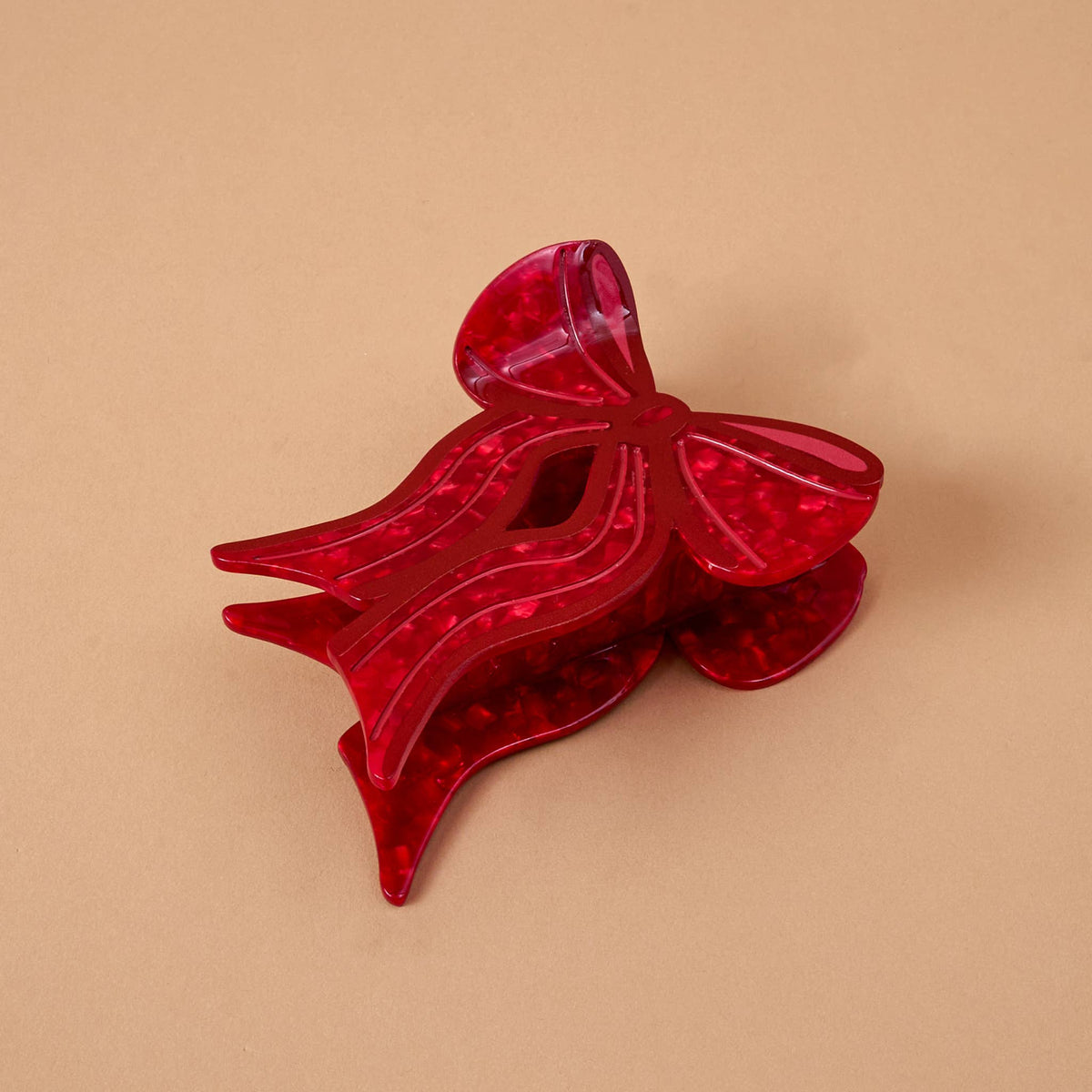 Red bow-shaped claw hair clip with glossy, translucent finish