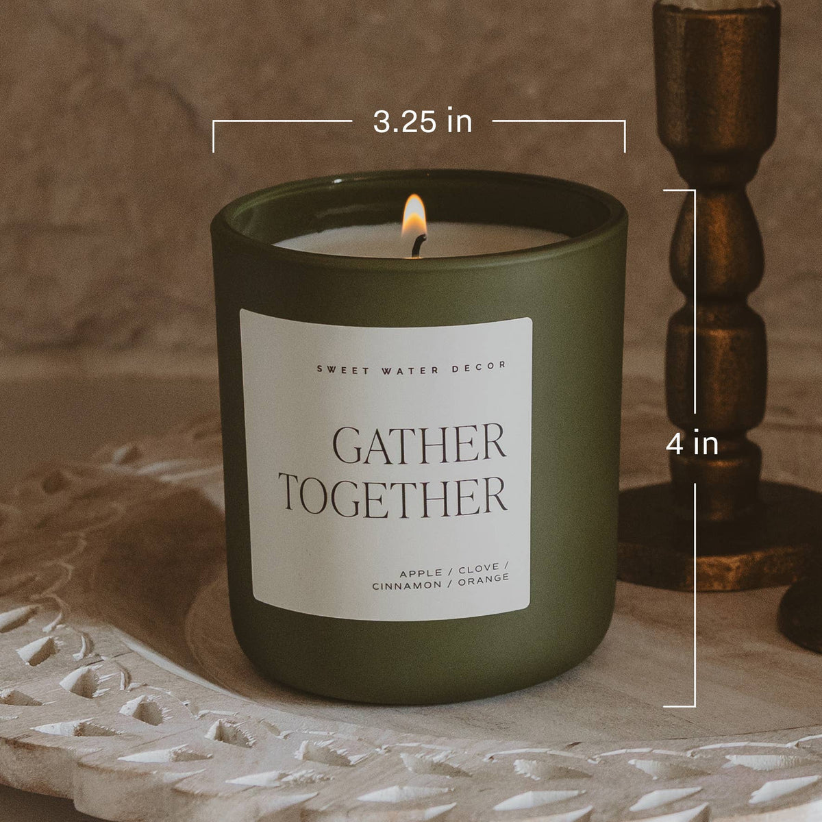 Olive green soy candle jar with lit wick and white label with small size markers