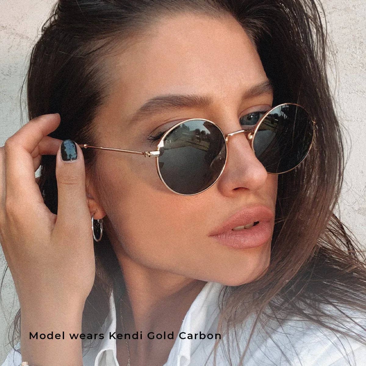 Round gold-tone sunglasses with dark lenses worn by model, thin metal frame