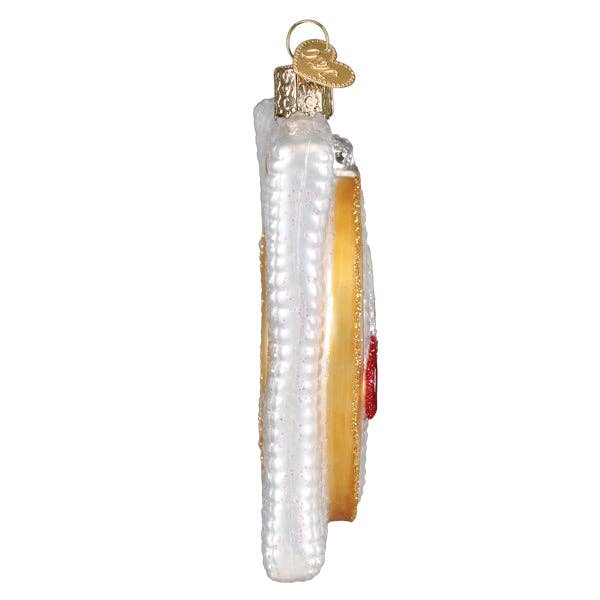 Side view of cross-stitch Christmas ornament with gold hanger and white textured backing