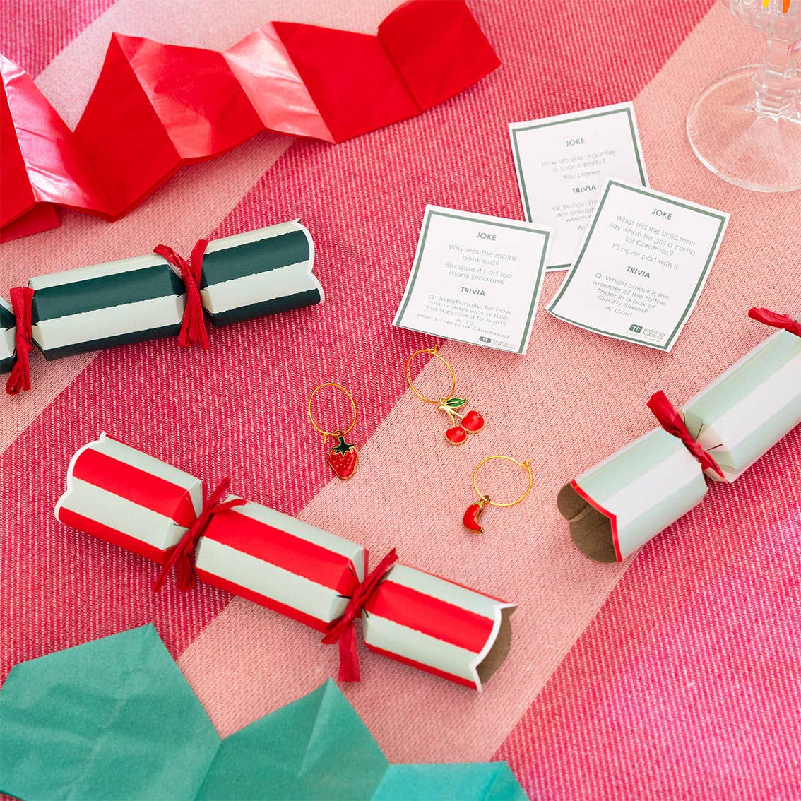 Mini Christmas crackers on a table: red ribbon-tied green and white striped rolls