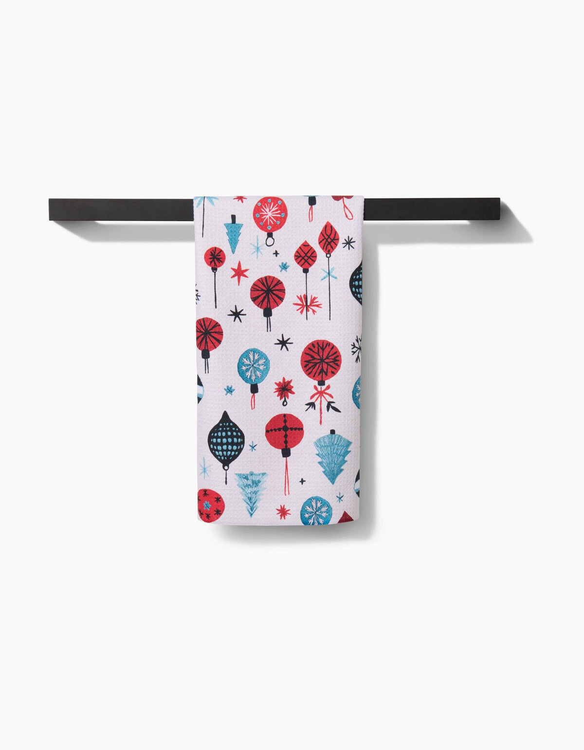 White tea towel hanging from a rod, embroidered ornaments in red and blue