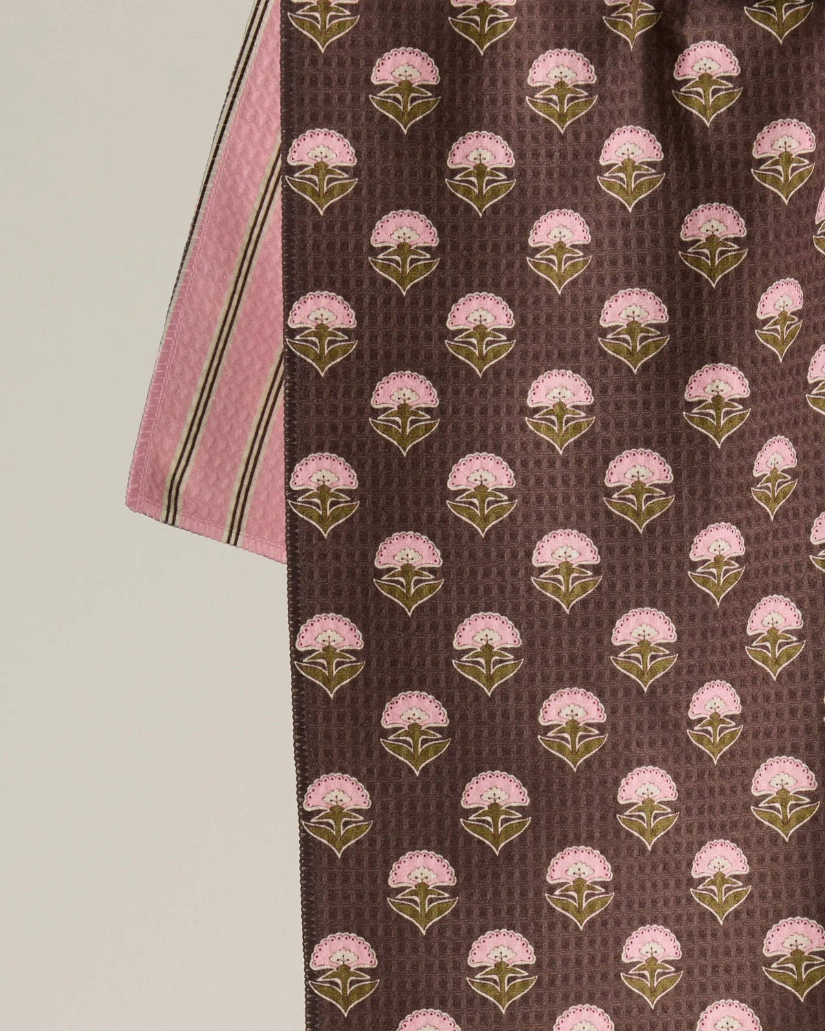 Close-up of dark brown kitchen towel fabric with pink and green floral motifs